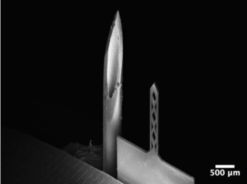 開孔鈦基微針（200um寬，50um厚，1500um長）和26G皮下注射針（外徑464um）對比的掃描電子顯微鏡照片